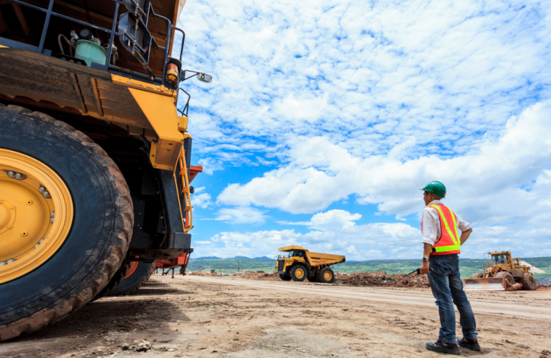 worker in mining stands in front of huge machinery